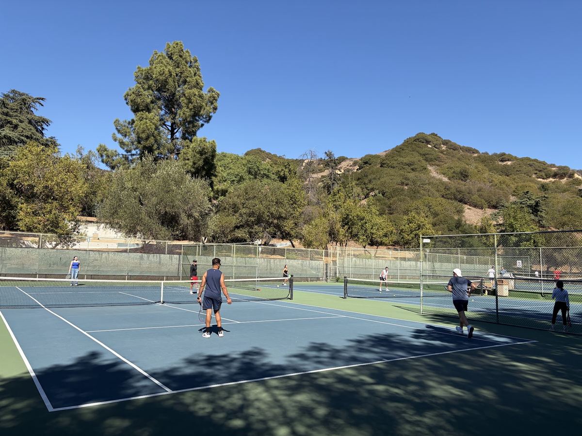 Players spread across several courts in continuous doubles play.