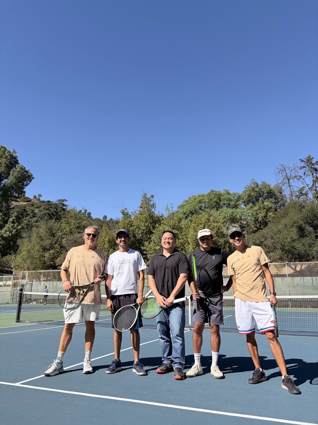 Five players standing at the net with racquets.